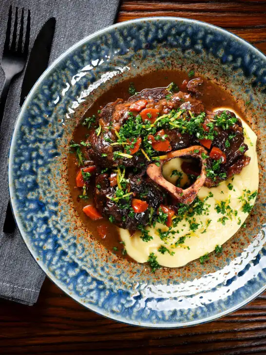 Overhead beef shin (shank) osso bucco served with polenta and gremolata.
