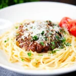 Beef pastitsada (Corfu) served with linguine pasta and tomato wedges and parmesan.