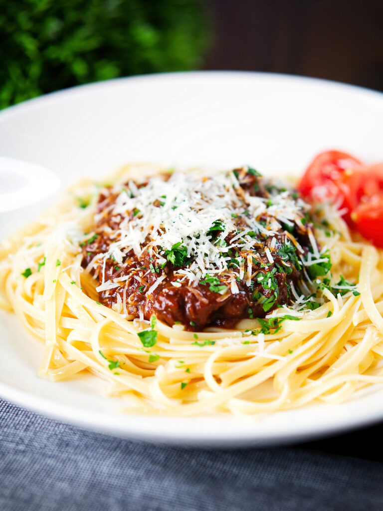 Beef pastitsada (Corfu) served with linguine pasta and tomato wedges and parmesan.