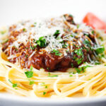 Close-up beef pastitsada (Corfu) served with linguine pasta and tomato and parmesan.