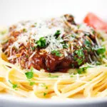 Close-up beef pastitsada (Corfu) served with linguine pasta and tomato and parmesan.