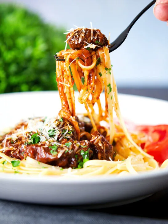 Beef pastitsada (Corfu) served with linguine pasta being eaten with a fork.