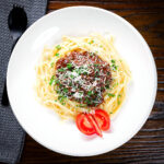 Beef pastitsada from Corfu served with linguine and tomato wedges.