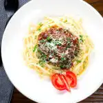 Overhead beef pastitsada (Corfu) served with linguine pasta and tomato and parmesan.