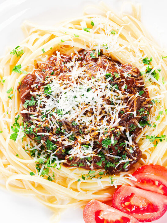Close-up overhead beef pastitsada (Corfu) served with linguine pasta and tomato and parmesan.