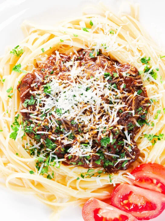 Close-up overhead beef pastitsada (Corfu) served with linguine pasta and tomato and parmesan.