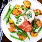 Overhead chicken wrapped in Parma ham stuffed with spinach and ricotta served with roasted new potatoes and green beans.