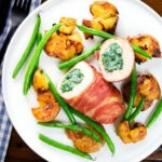 Overhead chicken wrapped in Parma ham stuffed with spinach and ricotta served with roasted new potatoes and green beans.