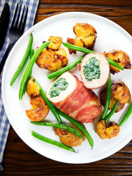 Overhead chicken wrapped in Parma ham stuffed with spinach and ricotta served with roasted new potatoes and green beans.