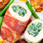 Close-up overhead chicken wrapped in Parma ham stuffed with spinach and ricotta served with roasted new potatoes and green beans.