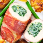 Close-up overhead chicken wrapped in Parma ham stuffed with spinach and ricotta served with roasted new potatoes and green beans.