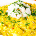 Close-up canned crab and saffron risotto served with dill and garlic bread.
