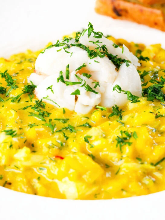 Close-up canned crab and saffron risotto served with dill and garlic bread.