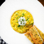 Overhead canned crab and saffron risotto served with dill and garlic bread.
