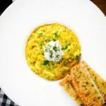 Overhead canned crab and saffron risotto served with dill and garlic bread.