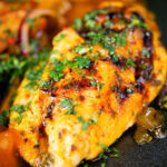 Close-up mango chutney chicken breast served with masala chips.