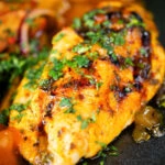 Close-up mango chutney chicken breast served with masala chips.