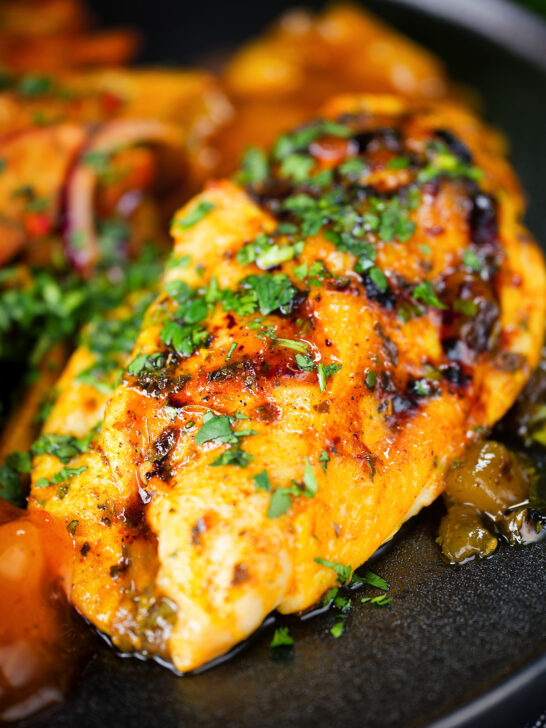 Close-up mango chutney chicken breast served with masala chips.