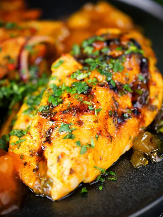 Close-up mango chutney chicken breast served with masala chips.