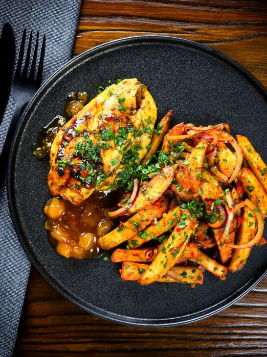 Overhead mango chutney chicken breast served with masala chips.