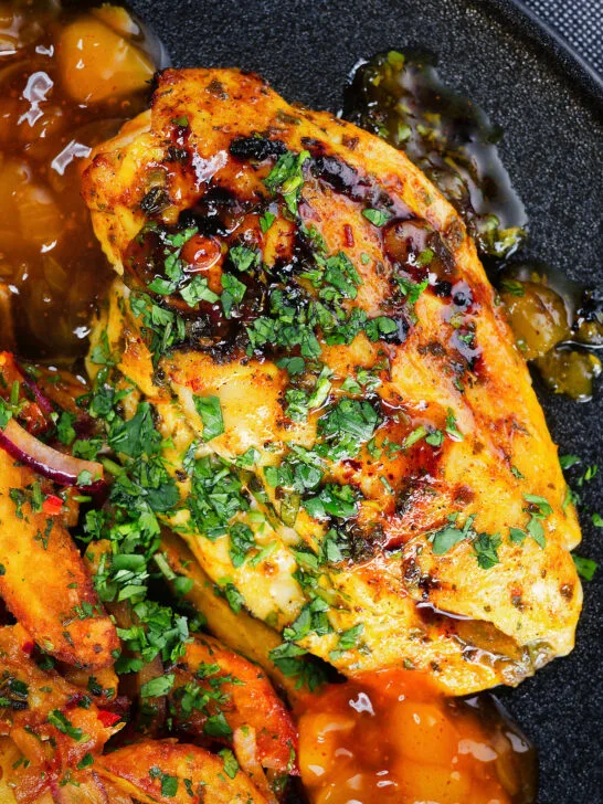 Close-up overhead mango chutney chicken breast served with masala chips.