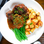 Overhead Spanish-influenced braised oxtail (rabo de toro) with mini roast potatoes and fine beans.