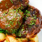 Overhead close up Spanish-influenced braised oxtail (rabo de toro) with mini roast potatoes.