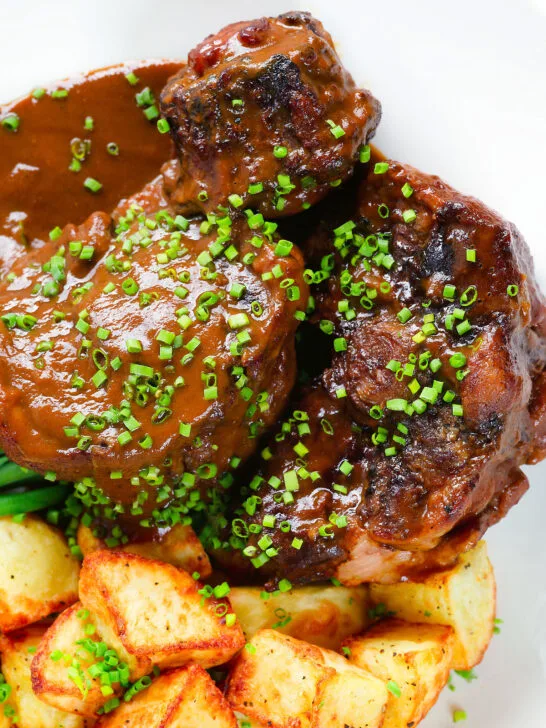 Overhead close up Spanish-influenced braised oxtail (rabo de toro) with mini roast potatoes.