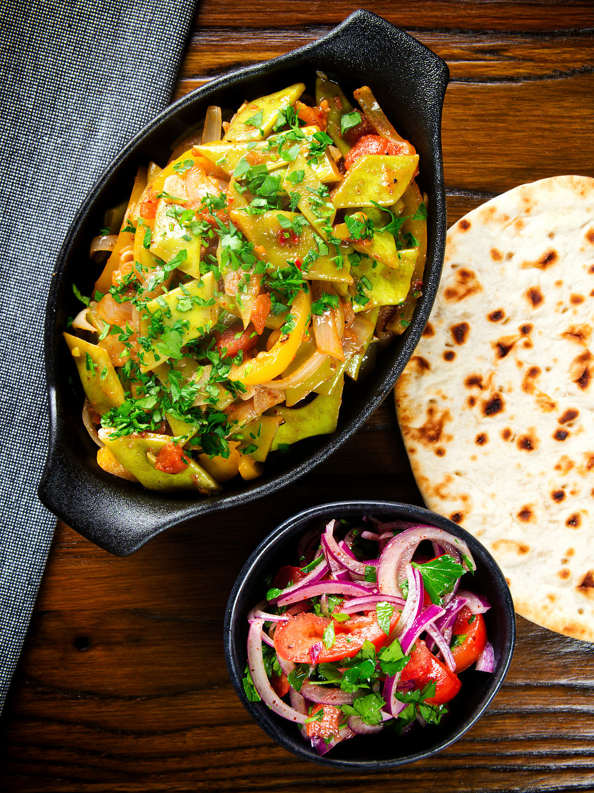Overhead taze fasulye (Turkish green bean stew) served with a side salad and flatbread.