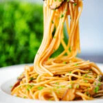 Vegetarian miso mushroom pasta (spaghetti) with snipped chives being picked up with a fork.