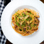 Overhead vegetarian miso mushroom pasta (spaghetti) with snipped chives.