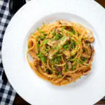 Overhead vegetarian miso mushroom pasta (spaghetti) with snipped chives.