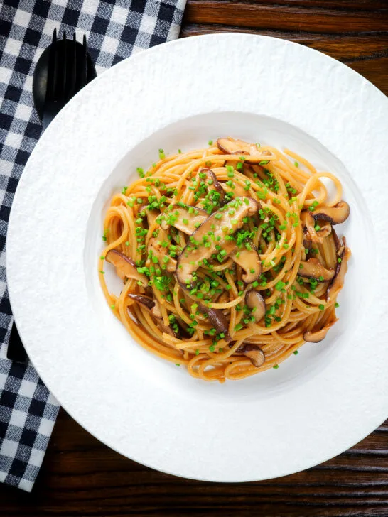 Overhead vegetarian miso mushroom pasta (spaghetti) with snipped chives.