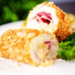 Close-up air fryer chicken cordon bleu with buttered potatoes and broccoli.