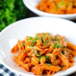 Spicy curry chicken pasta with Indian influences garnished with coriander.