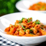 Curry tomato chicken pasta with Indian influences garnished with coriander.