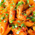 Close-up curry chicken pasta with Indian influences garnished with coriander.