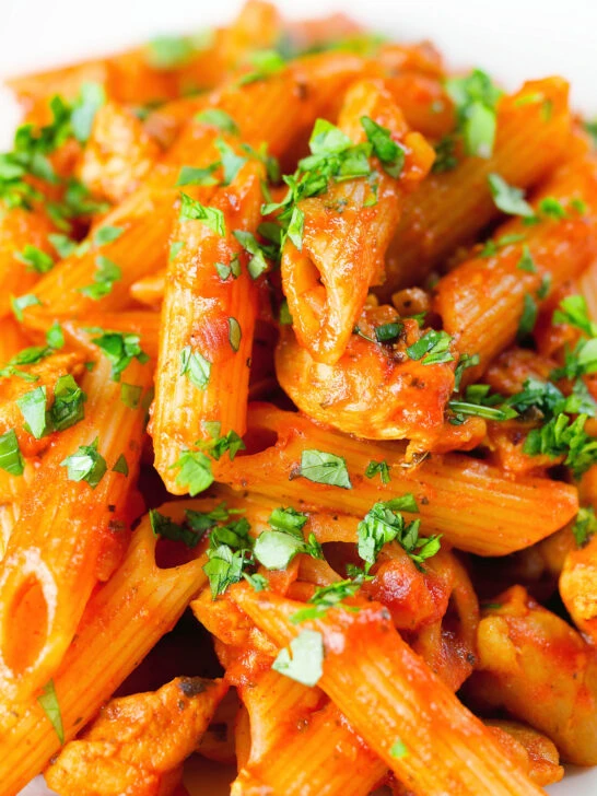 Close-up curry chicken pasta with Indian influences garnished with coriander.