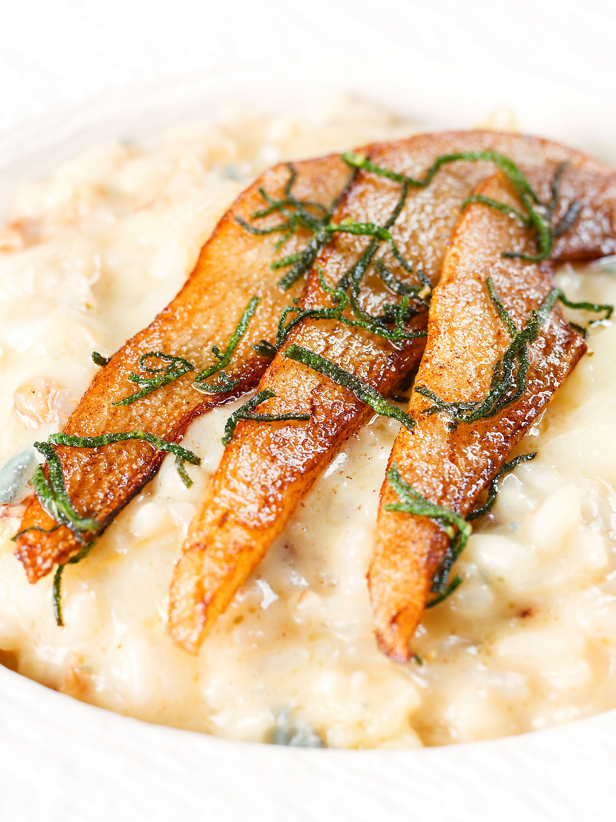 Close-up pear, walnut and Gorgonzola risotto with fried pear slices.