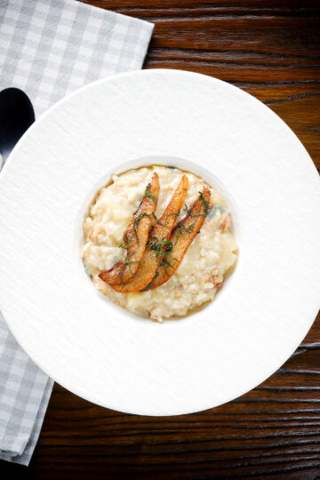 Overhead pear, walnut and Gorgonzola risotto with fried pear slices.