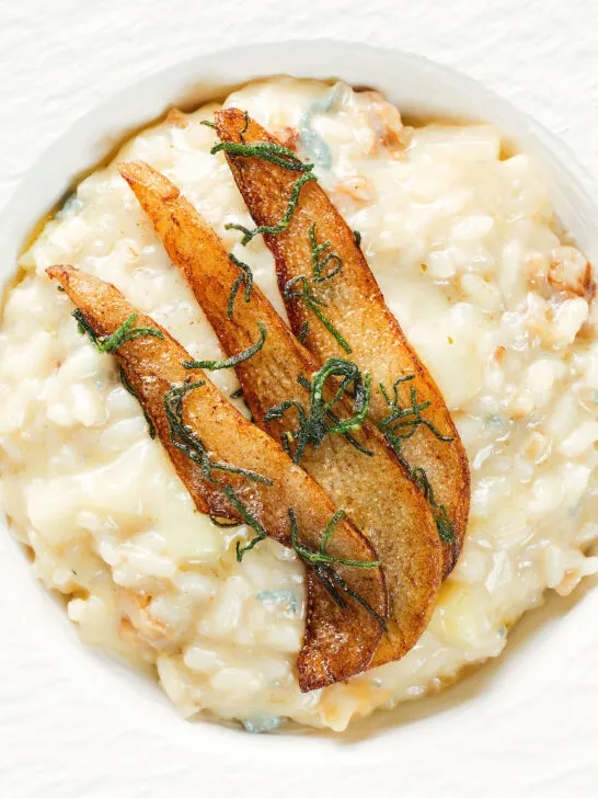 Close-up overhead pear, walnut and Gorgonzola risotto with fried pear slices.