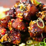 Close-up crispy Chinese salt and pepper pork belly bites with pak choi and Jasmine rice.