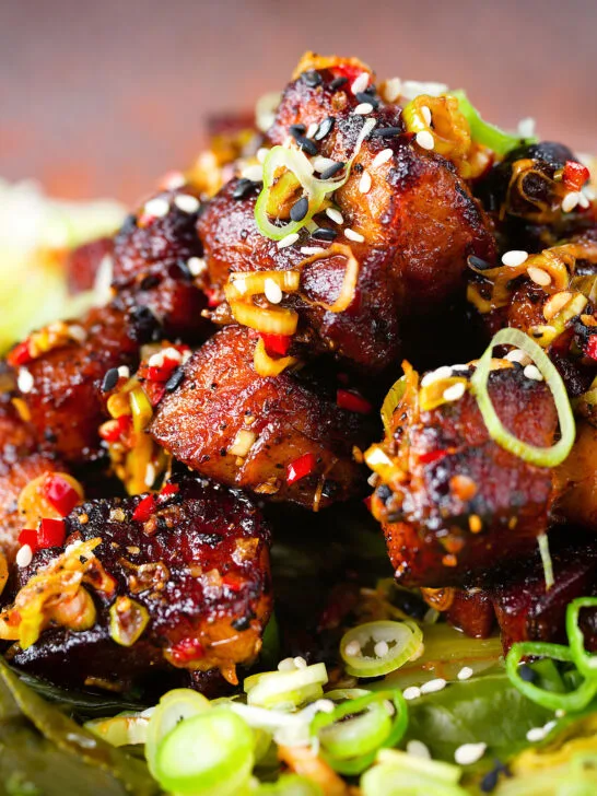 Close-up crispy Chinese salt and pepper pork belly bites with pak choi and Jasmine rice.
