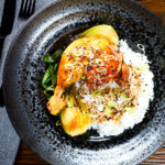 Overhead Chinese influenced soy sauce braised chicken leg with pak choi and rice.