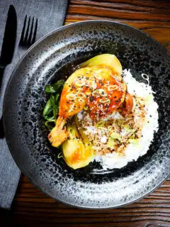 Overhead Chinese influenced soy sauce braised chicken leg with pak choi and rice.