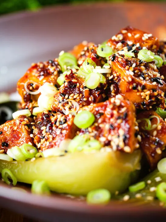 Close-up spicy sticky sesame tofu served with pak choi and jasmine rice.