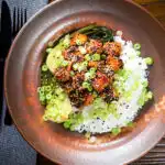 Overhead spicy sticky sesame tofu served with pak choi and jasmine rice.