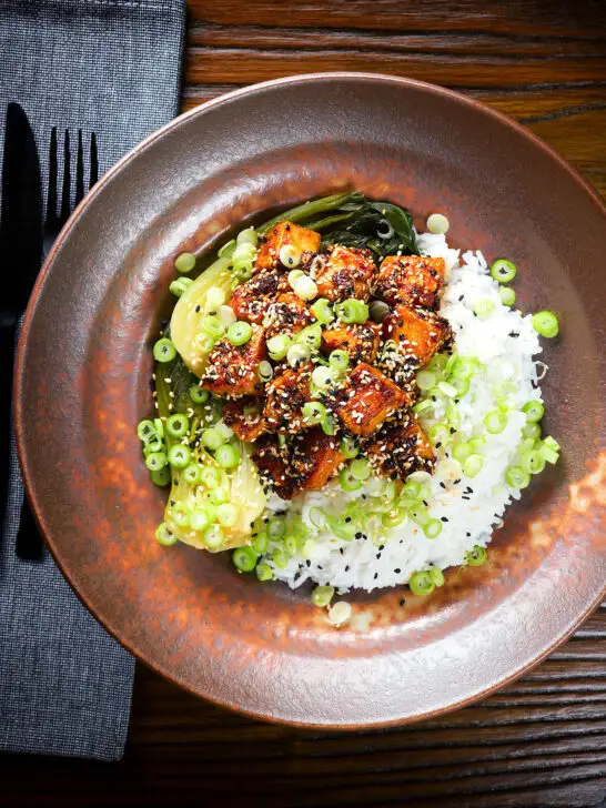 Overhead spicy sticky sesame tofu served with pak choi and jasmine rice.