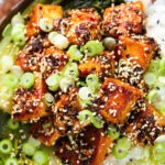 Close-up overhead spicy sticky sesame tofu served with pak choi and jasmine rice.
