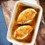 Overhead sticky orange marmalade roasted chicken breasts with fennel seeds in a baking dish.